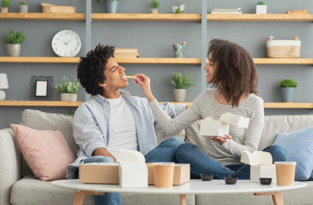 Finished Home Repairs with Personal Loan Happy couple eating takeout in their updated living room after completing a major home repair funded by a personal loan.