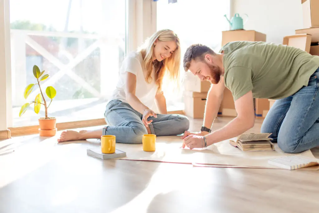 Planning Home Improvement Loan Projects A couple sitting on the floor with blueprints and boxes, outlining home improvement loan projects.