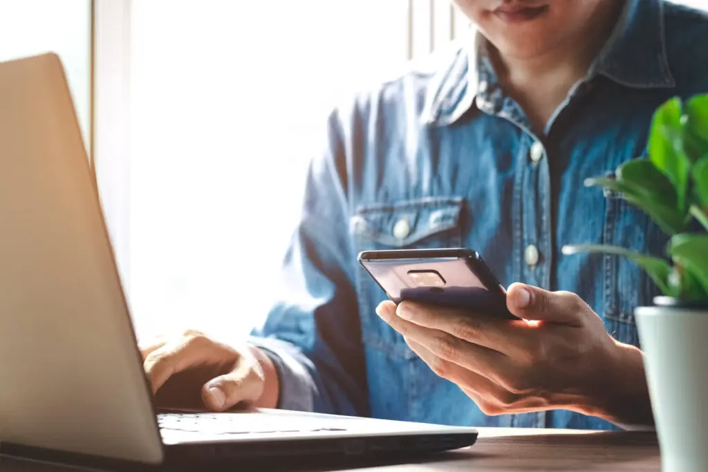 Comparing Top $20,000 Personal Loans A person using a smartphone and laptop to compare top $20,000 personal loan offers.