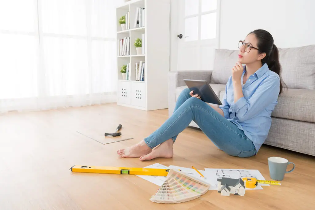 Comparing Personal Loans for Home Remodeling A person sitting on the floor with a tablet, looking at the ceiling while contemplating personal loan options to fund a home remodel.
