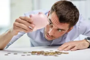 Person holding a piggy bank upside down with coins falling out to get quarters for change.