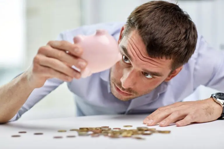 Person holding a piggy bank upside down with coins falling out to get quarters for change.