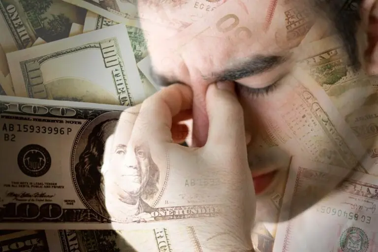 Person looking distressed while holding their head, surrounded by money, illustrating the link between mental health and financial struggles.