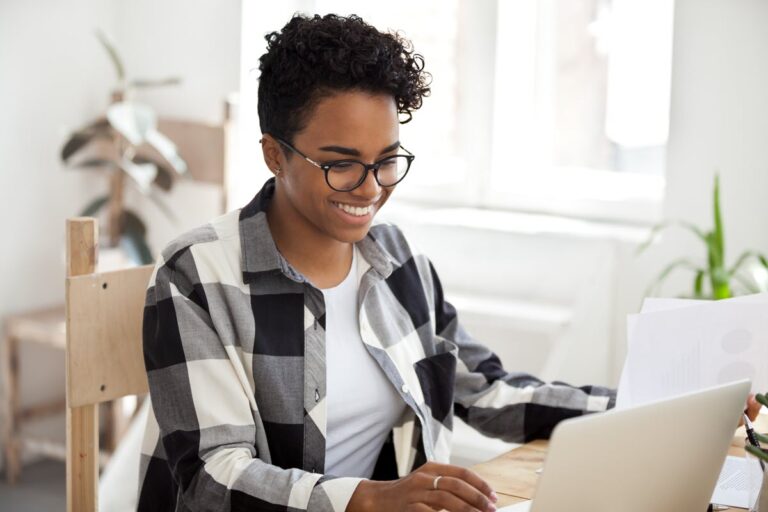 Smiling person at a laptop researching 25 proven ways to borrow 500 dollars fast.