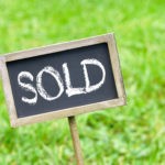 Vacant land sold sign in grass.