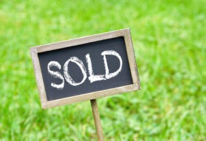 Vacant land sold sign in grass.