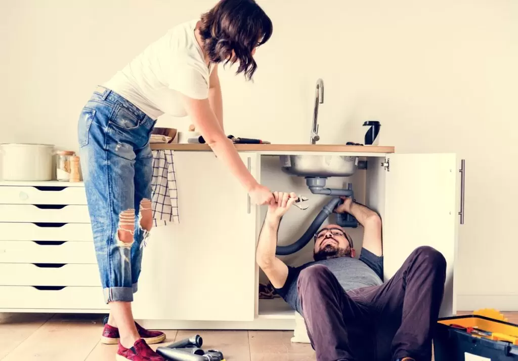White couple fixing kitchen sink. White couple fixing kitchen sink.