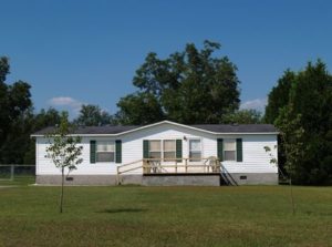White single-wide mobile home on land lot.